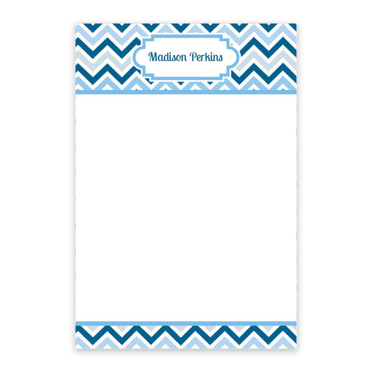 The Noteworthy Multi Blue Chevron Personalized Notepad features blue and white chevron borders, a blank center, and "Madison Perkins" elegantly printed at the top. With 50 sheets, it adds a stylish touch to any desk.