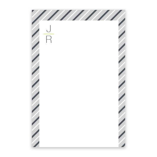 The Pinstripe Initials Personalized Notepad by Noteworthy features a white center, diagonal gray and navy striped borders, and “J” above “R” in the top left. Available with 50 or 100 sheets.