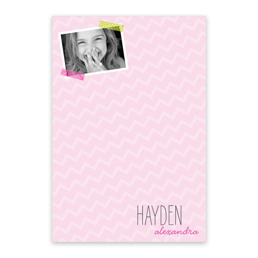 The Pink Chevron Personalized Notepad with Photo by InvitationBox.com features a black-and-white child’s photo taped at the top left and "Hayden alexandra" at the bottom right—perfect for creating custom stationery.