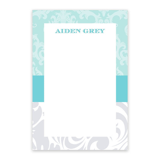 The Banded Blue Toile Personalized Notepad by Noteworthy features a rectangular design with ornate blue and gray borders, baby blue toile pattern, "AIDEN GREY" at the top, and is available in 50 or 100 sheets.