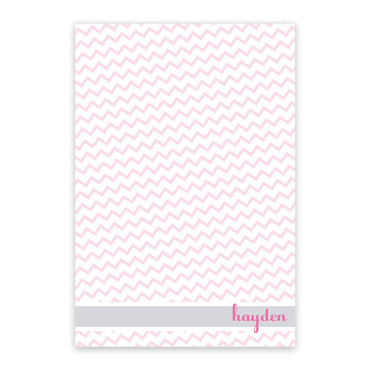 The Noteworthy Pink Chevron Personalized Notepad features a white and pink chevron design, a gray stripe near the bottom, and "hayden" in pink lowercase letters on the lower right—ideal for custom notes.