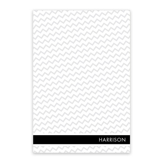 The Gray Chevron Personalized Notepad by Noteworthy features white paper with a gray chevron pattern and a black band at the bottom for your name—a stylish touch to any desk.