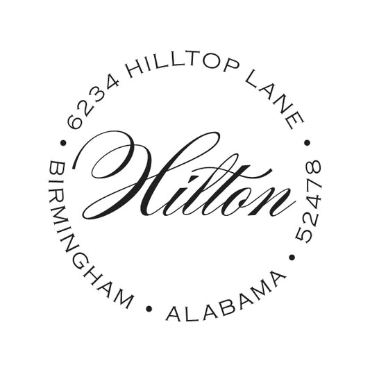 The Noteworthy Exquisite Name Stamper or Embosser features "Hilton" in script at the center and "6234 Hilltop Lane, Birmingham, Alabama, 52478" around the edge—ideal for personalizing stationery with a circular address design.