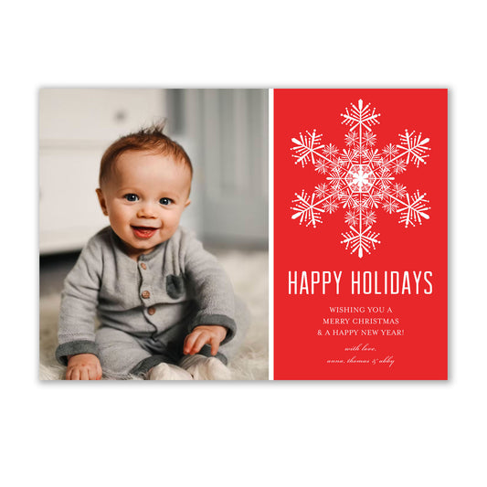 An Elegant Snowflake Holiday Photo Cards baby sitting on the floor. (Brand Name: Noteworthy)