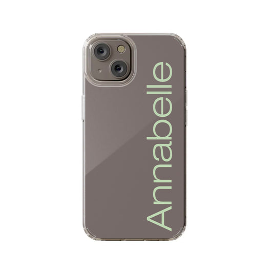 An iPhone 14 with the Custom Side Name Clear Case by InvitationBox.com, showcasing "Annabelle" in large, light-colored vertical text on a taupe background.