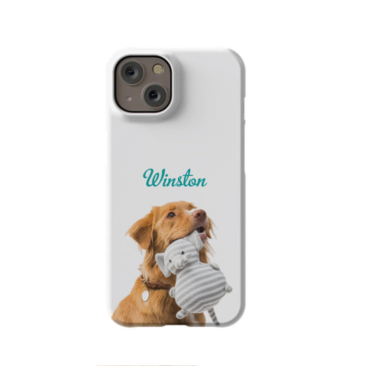 The Custom Cutout iPhone 14 Slim Case from InvitationBox.com features a brown dog with a collar holding a gray striped cat plush toy and "Winston" above, creating a unique personalized gift for pet lovers.